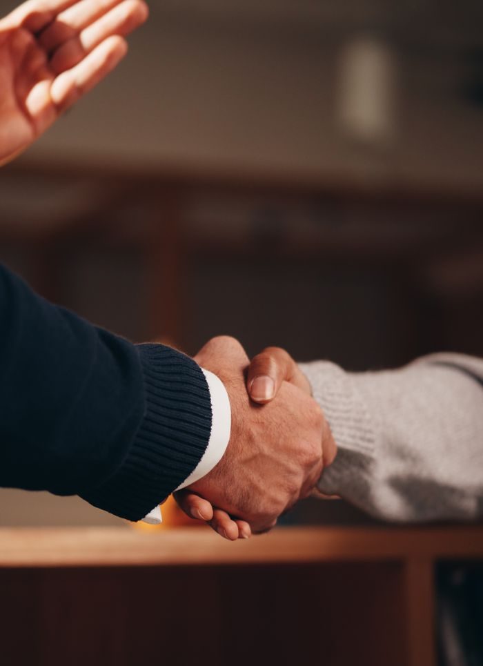 Two hands shaking in a professional setting, symbolizing business deal or agreement.